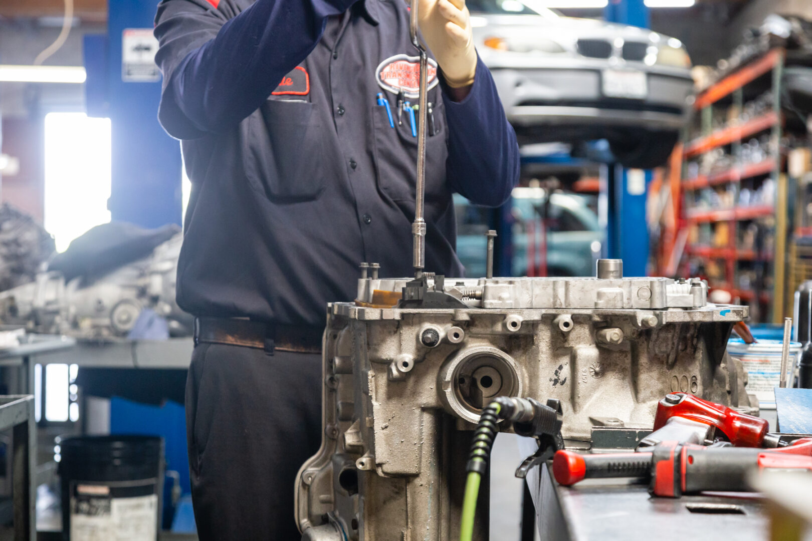 A man in blue shirt holding wrench near engine.